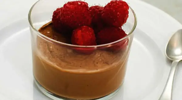 En krämig choklad pannacotta toppad med färska hallon i ett glas. En perfekt dessert för alla chokladälskare.