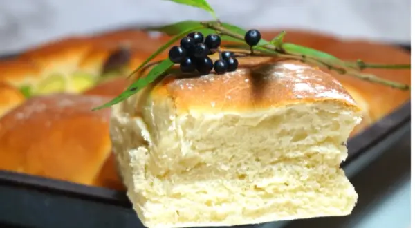 Nybakade, fluffiga tekakor i långpanna, dekorerade med en kvist med svarta bär och gröna blad. Perfekt för fika!