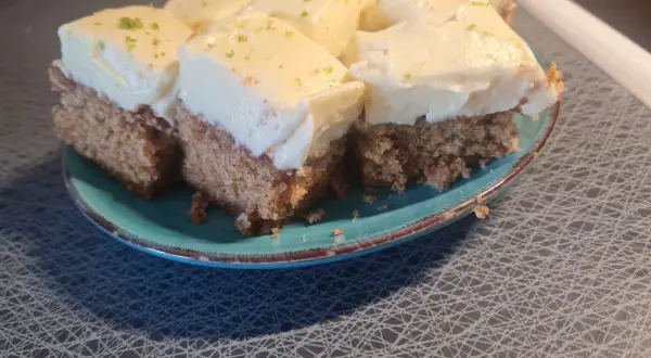 Sju bitar morotskaka med vit frosting och rivet citronskal på en turkos tallrik. Bra att veta att man kan frysa in morotskaka för senare njutning.