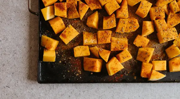 Tärnad pumpa kryddad och redo för ugnen. Ett enkelt steg i ett gott pumpapure recept.