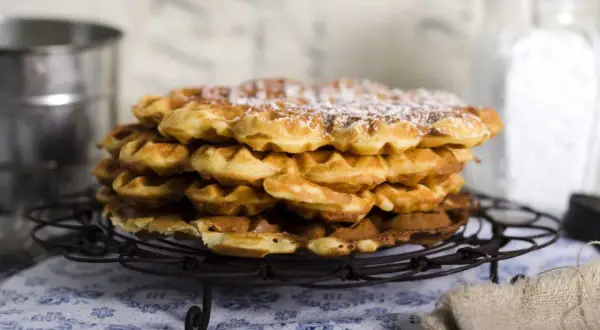 En hög med nybakade, pudrade våfflor som väntar på att serveras. Perfekt för en mysig fika.