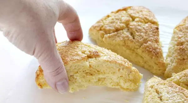 En hand plockar en gyllene scones. Bra att veta om man kan frysa scones för senare njutning.