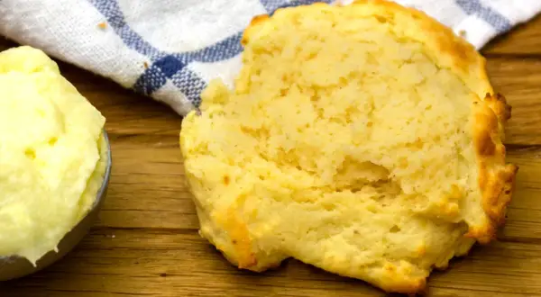 En fluffig scone bredvid en skål med mjukt, flytande margarin, redo att avnjutas.