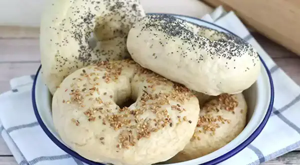 Färska bagels med vallmofrön och sesamfrön i en skål, redo för ditt bagels recept.