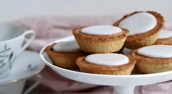 En hög med hembakade mazariner med vit glasyr, redo att avnjutas. Perfekt för ett fika-tillfälle, kanske med ett gott mazariner recept.