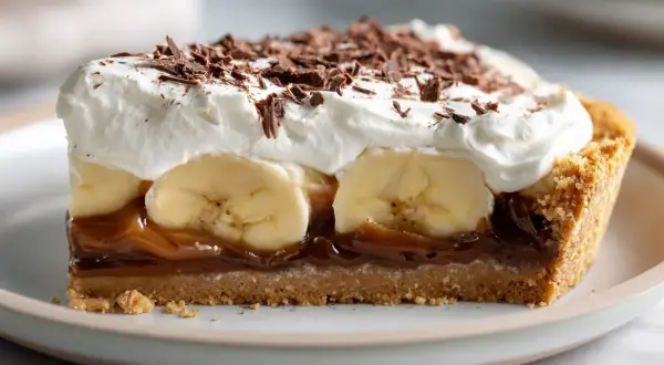 En bit krämig banoffee paj med banan, kolasås, vispgrädde och chokladströssel.