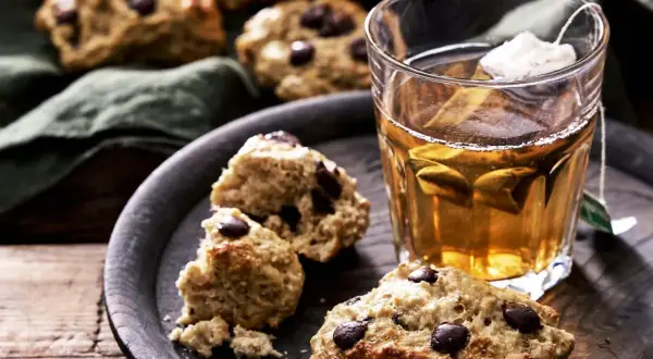 Choklad scones på ett fat med en kopp te. En härlig fika, men tänk på scones kalorier om du vill hålla koll.