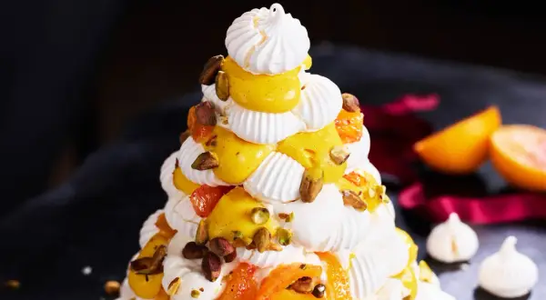 Julig pavlova i juletid, dekorerad med krämig vaniljkräm, aprikoser och pistagenötter.