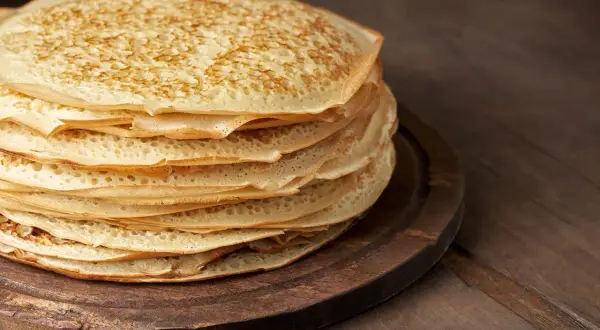 En hög med gyllene pannkakor på en träbricka, redo att frysa in pannkakor för framtida frukostar.