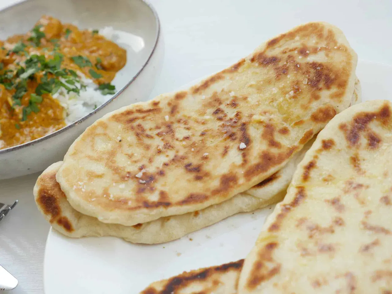 Nybakade, gyllene naanbröd med strössel av flingsalt, perfekta till en krämig curry. Ett enkelt naan recept för hemmabruk.