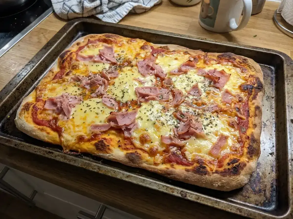 En nybakad pizza med skinka och ost på en plåt. Perfekt för en snabb middag med snabb pizzadeg!