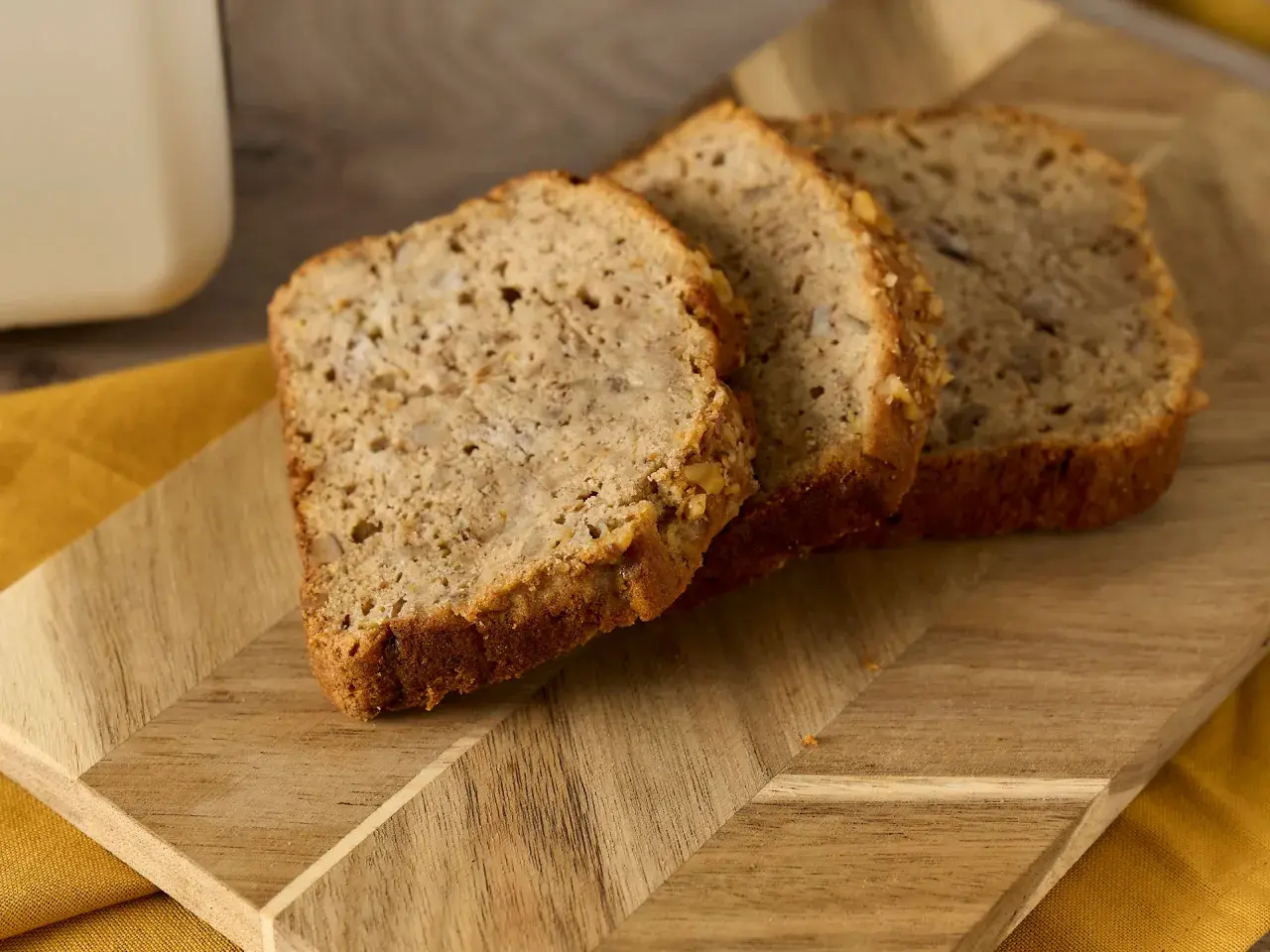 Skivor av bananbröd på en träskärbräda. Frågan "hur länge kan man frysa bröd" dyker upp när man ser hur färskt det ser ut.