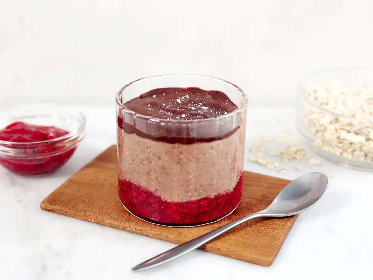 Choklad overnight oats med hallon och en sked redo att avnjutas.