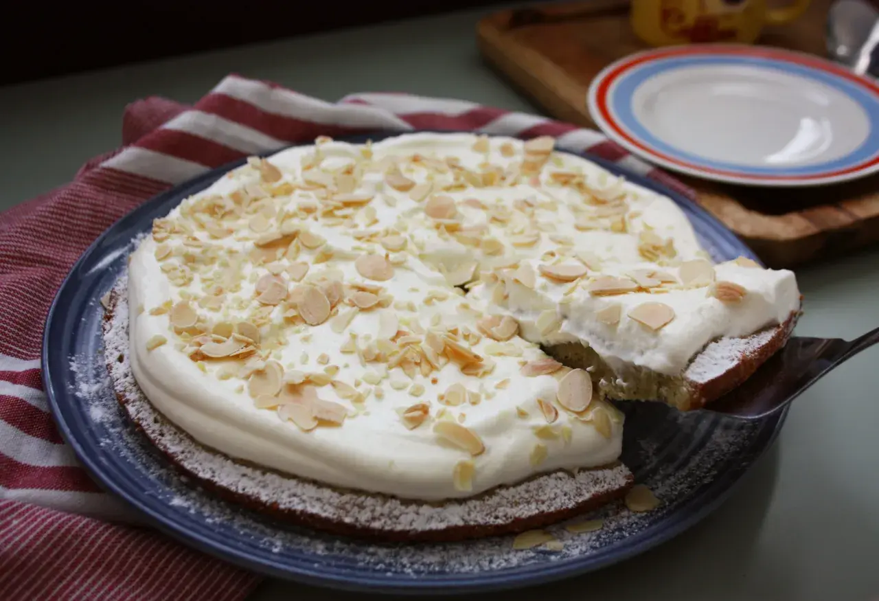 En saftig semmelkladdkaka med fluffig grädde och mandelmassa, toppad med mandelspån. En dröm för alla fikasugna!