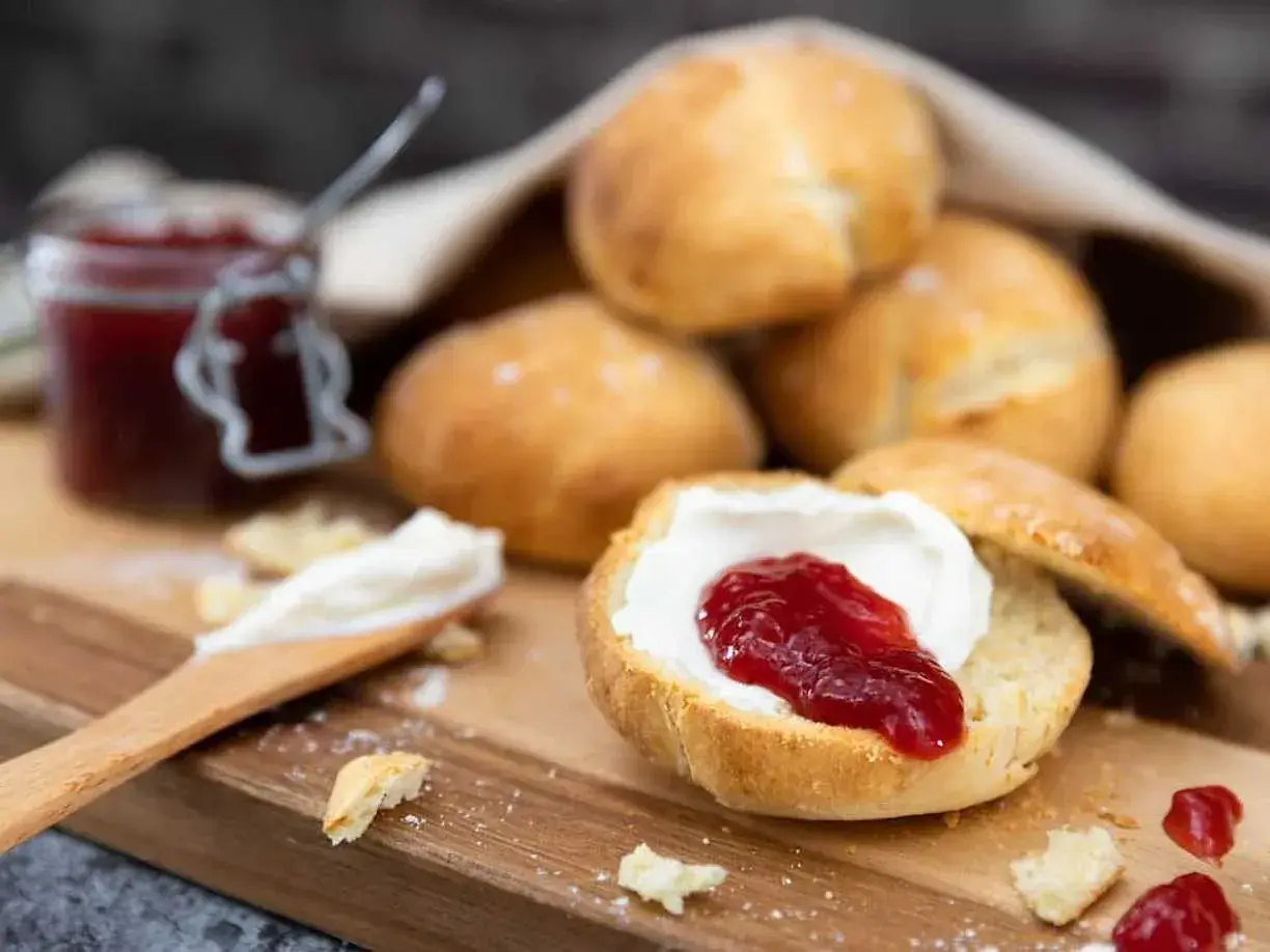 Lyxiga scones med grädde och sylt på en träbricka. En härlig fika!