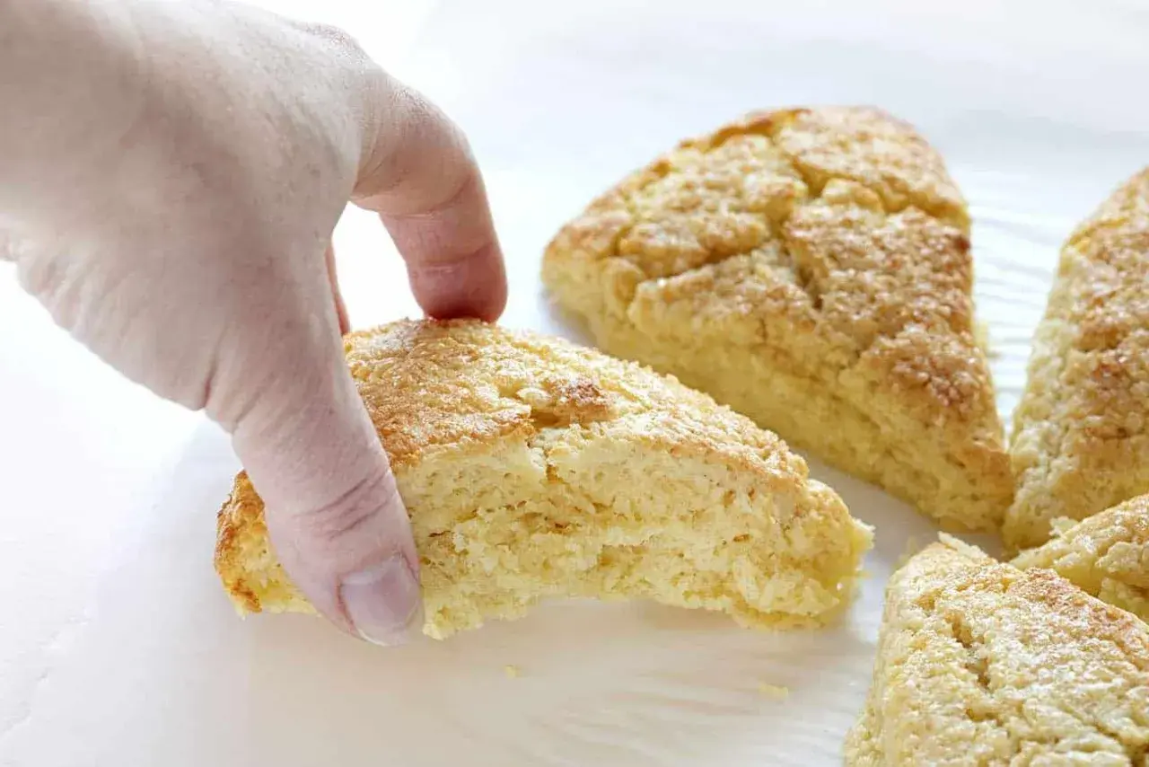 En hand plockar en gyllene scones. Bra att veta om man kan frysa scones för senare njutning.