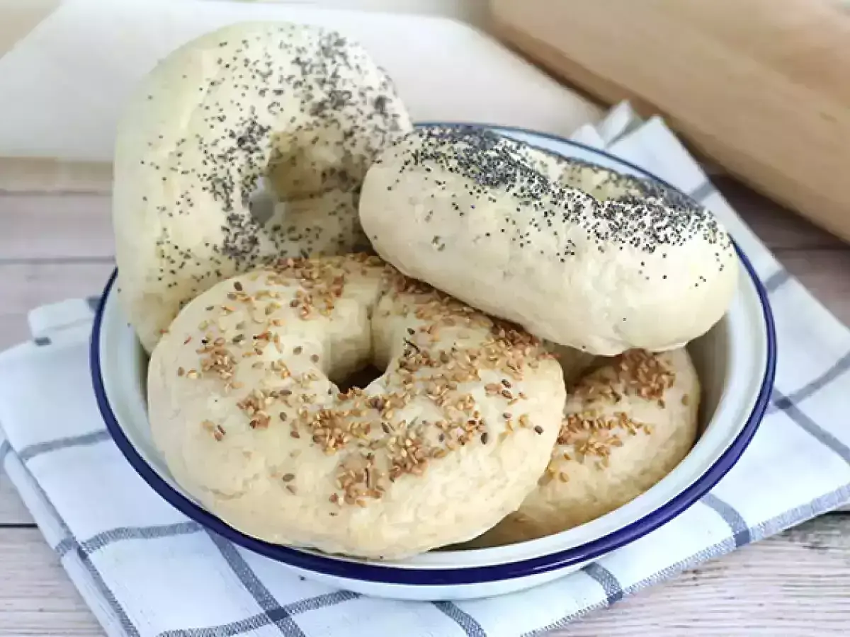 Färska bagels med vallmofrön och sesamfrön i en skål, redo för ditt bagels recept.