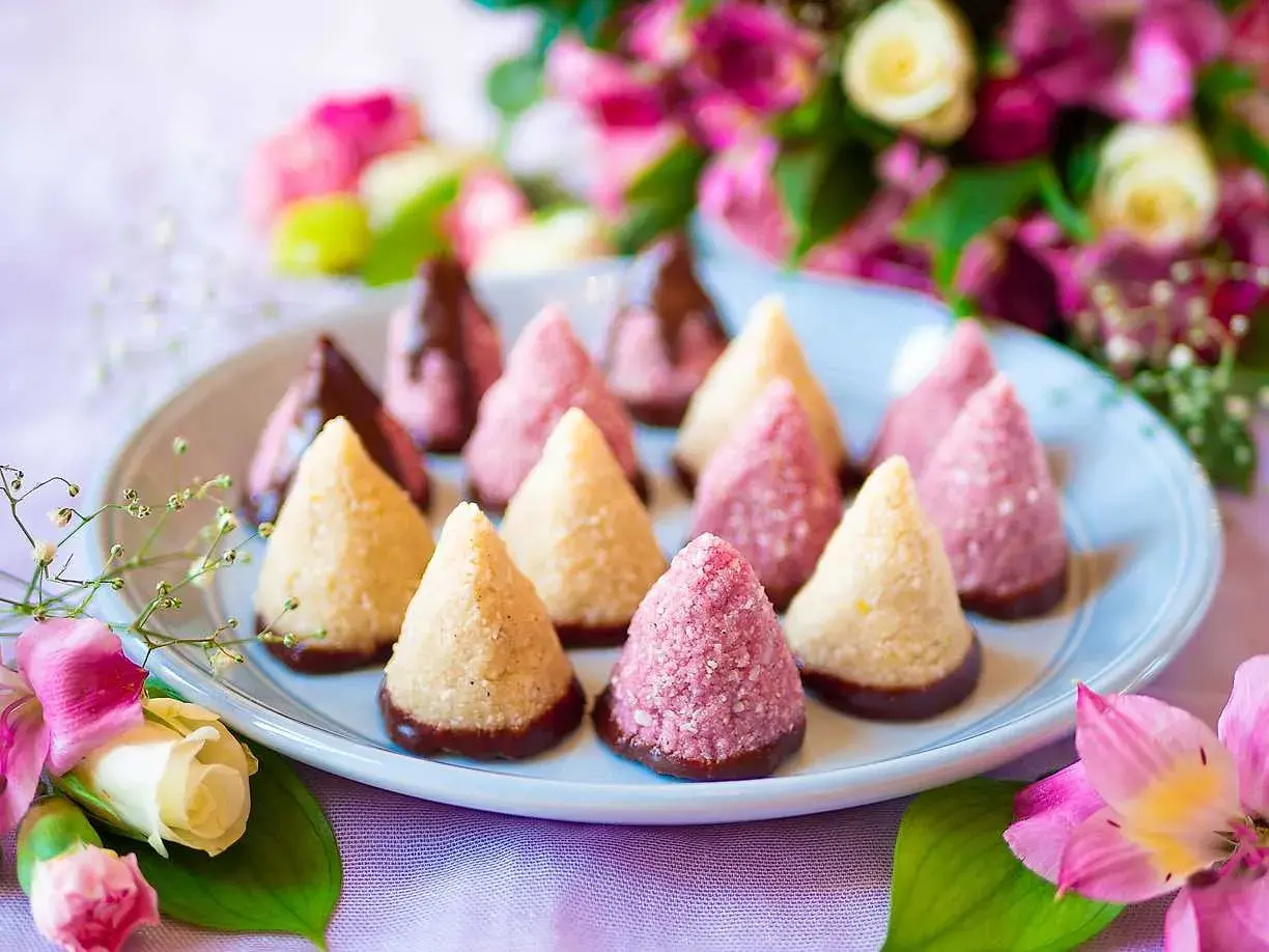 En tallrik med enkla kakor, några doppade i choklad, omgivna av blommor. Perfekt för fika.