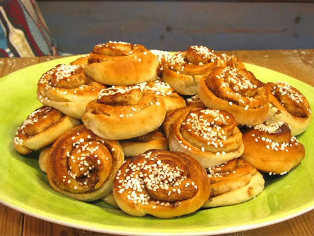 En hög med nybakade kanelbullar, perfekta att baka med mycket mjölk för extra saftighet. Strösslade med pärlsocker.