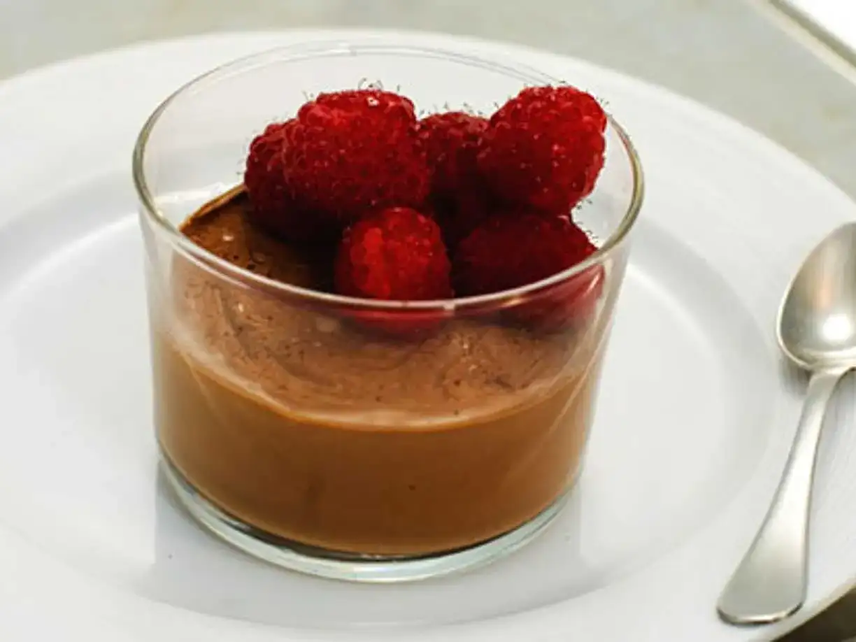 En krämig choklad pannacotta toppad med färska hallon i ett glas. En perfekt dessert för alla chokladälskare.