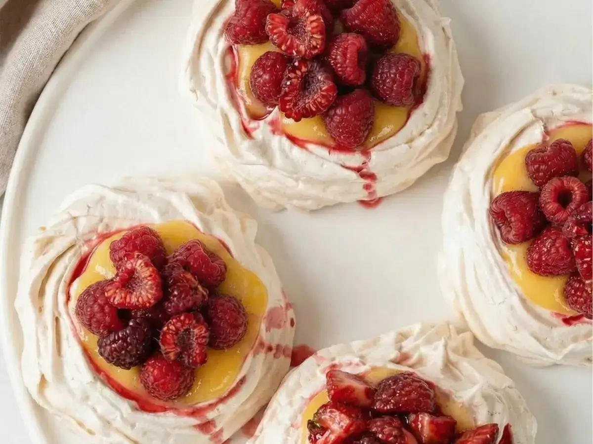 Små marängbottnar fyllda med krämig lemoncurd och toppade med färska hallon och jordgubbar. En härlig pavlova!
