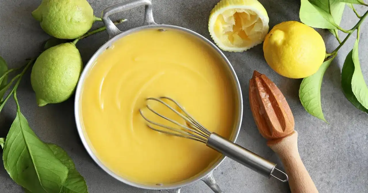 Kastrull med krämig lemon curd, färska citroner och en träpress. Perfekt för bakning!