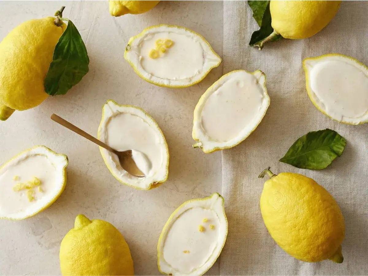 Citroner fyllda med kr&auml;mig dessert, som en h&auml;rlig k&auml;rleksmums p&aring;sk. En gyllene sked vilar i en citronhalva.