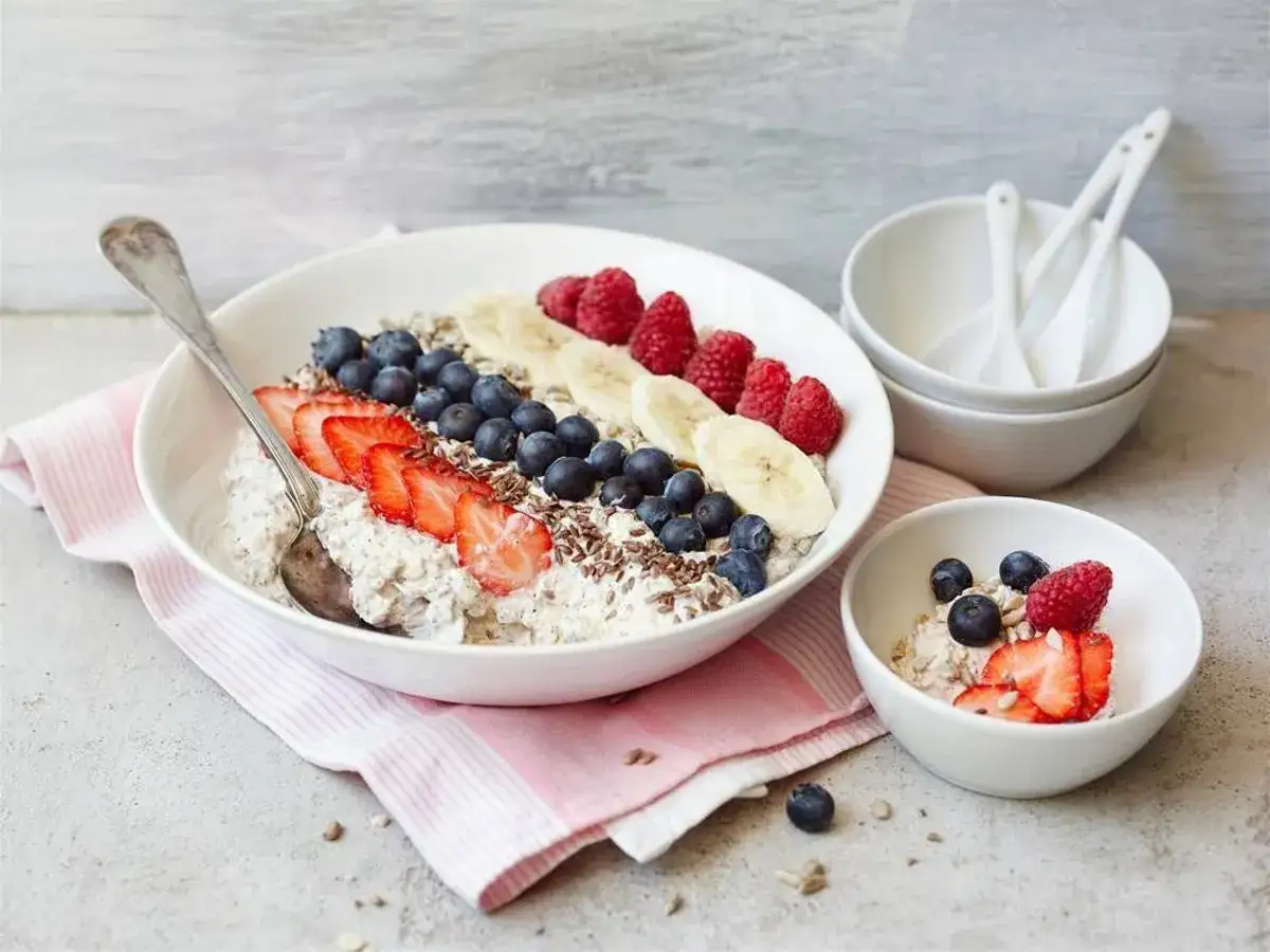 En sk&aring;l med gr&ouml;t toppad med jordgubbar, bl&aring;b&auml;r, hallon och banan. En mindre sk&aring;l med samma topping. Filmj&ouml;lk vs kefir &ndash; en h&auml;lsosam frukost.