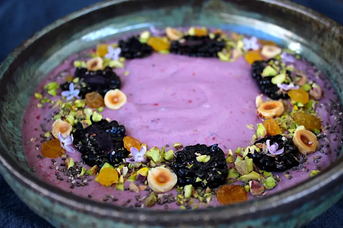 En vacker smoothie bowl med hallon, björnbär, nötter, pistagenötter och chiafrön.