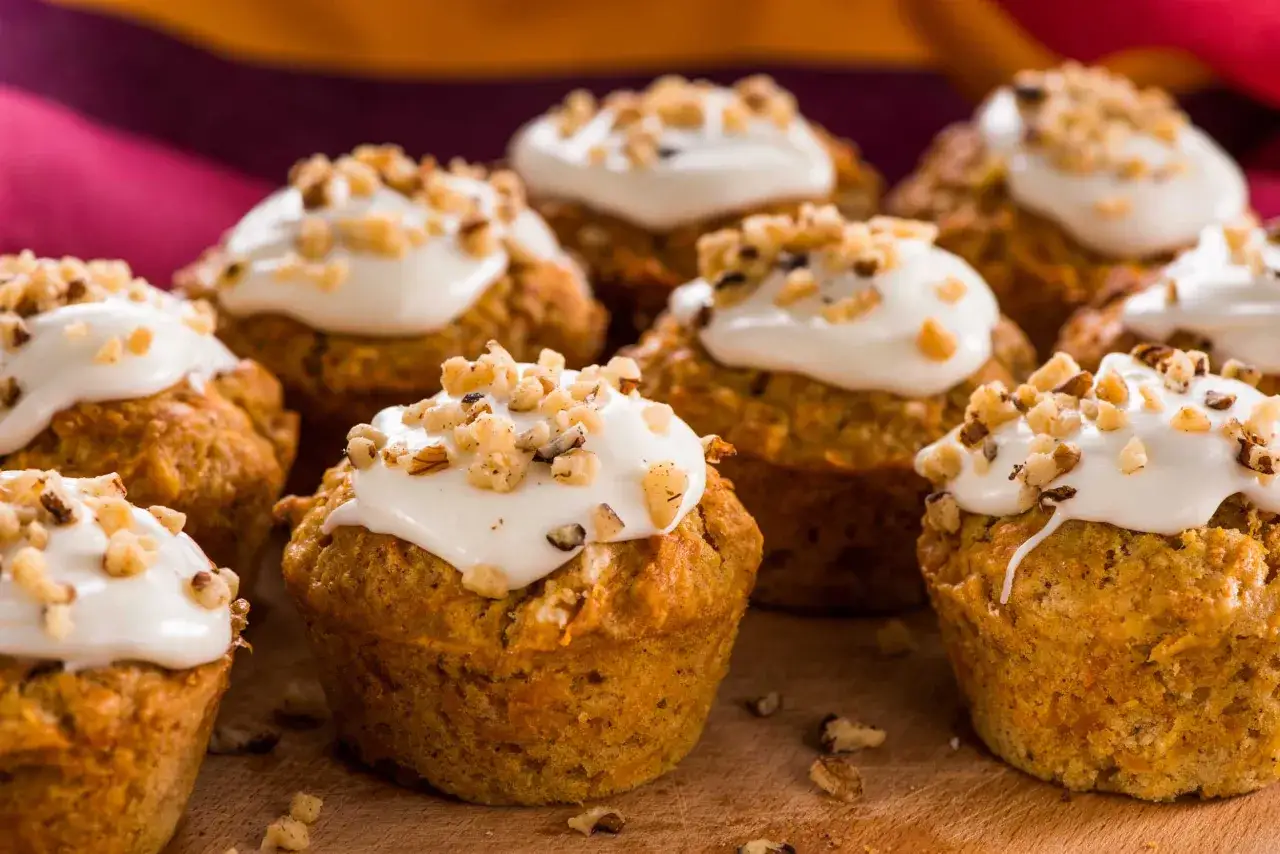 En grupp saftiga morotskaka muffins med krämig frosting och hackade nötter. Perfekta för fikat!