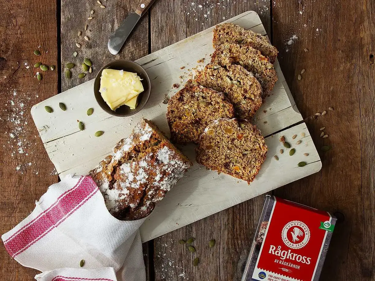Nybakad fil bröd med frön och torkad frukt, serverad med smör och en förpackning RågKross.