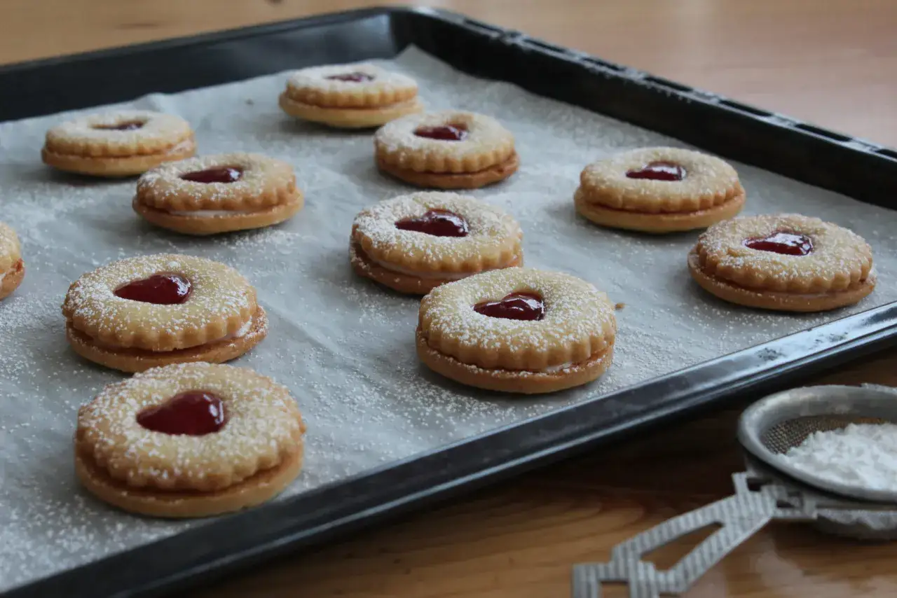 Färdiga syltkakor med hjärtformad sylt och pudrat florsocker, redo att avnjutas. Ett enkelt syltkakor recept för hembakning.