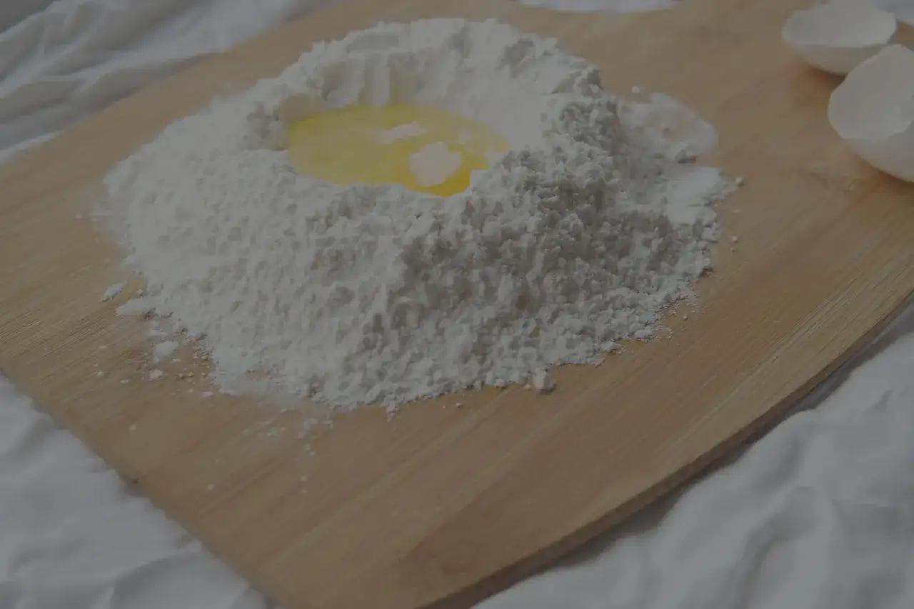 Mjöl och ett ägg på en skärbräda, redo att blandas. Kanske för att baka med bikarbonat istället för bakpulver?