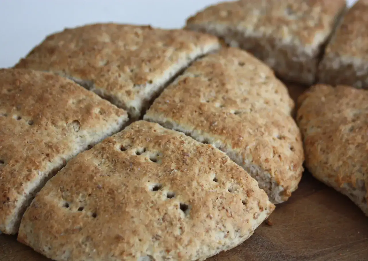 En n&auml;rbild p&aring; nybakade scones med grahamsmj&ouml;l, uppskurna i trianglar och redo att avnjutas.