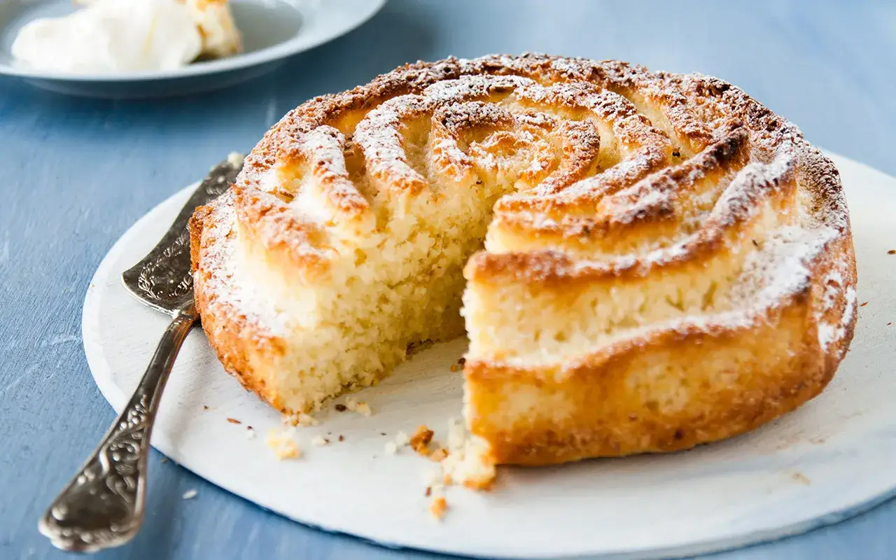 En saftig sockerkaka med citronsmak, pudrad med florsocker. En bit &auml;r uppskuren, redo att serveras.