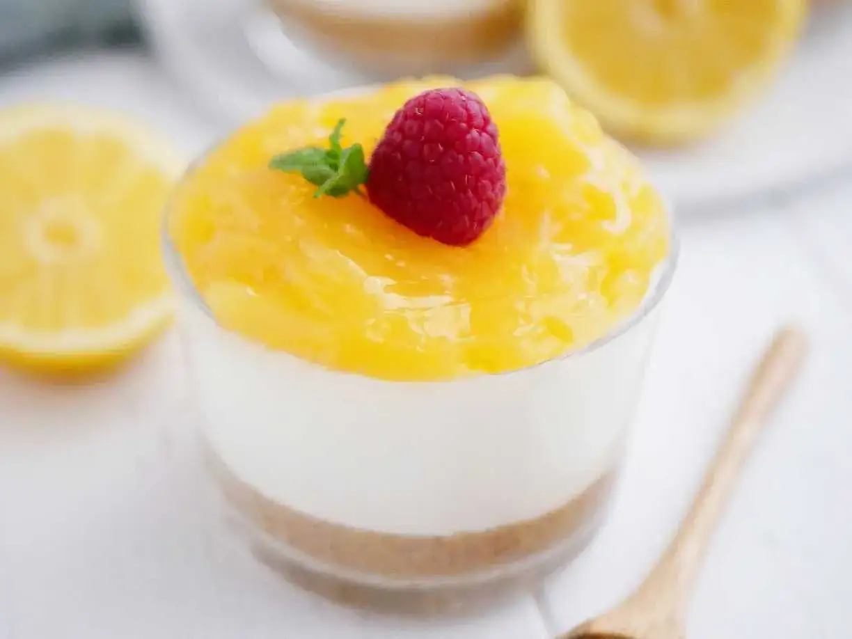 En läcker citron cheesecake i glas, toppad med hallon och mynta. Perfekt för en somrig fika.
