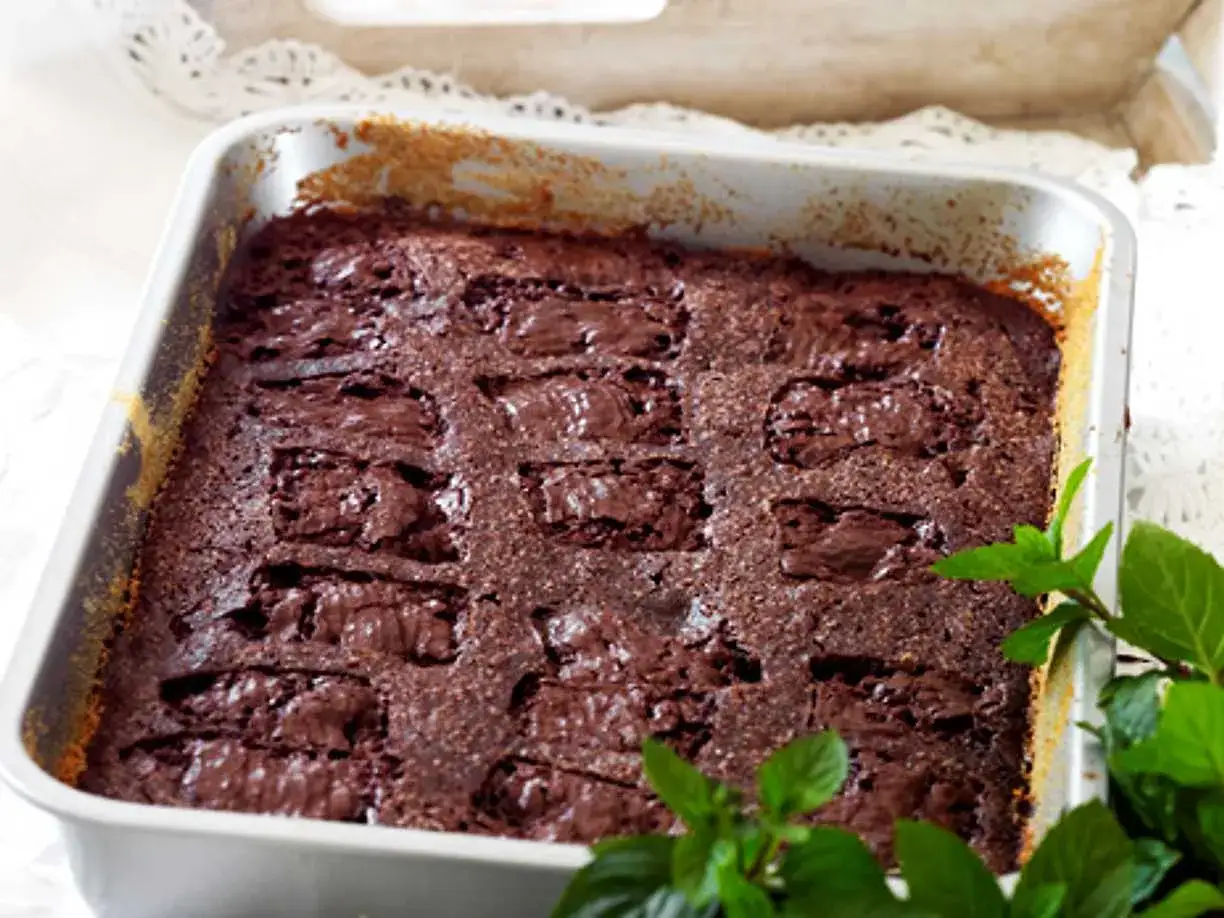 En nybakad kladdkaka med After Eight-chokladbitar i en form, dekorerad med myntablad.