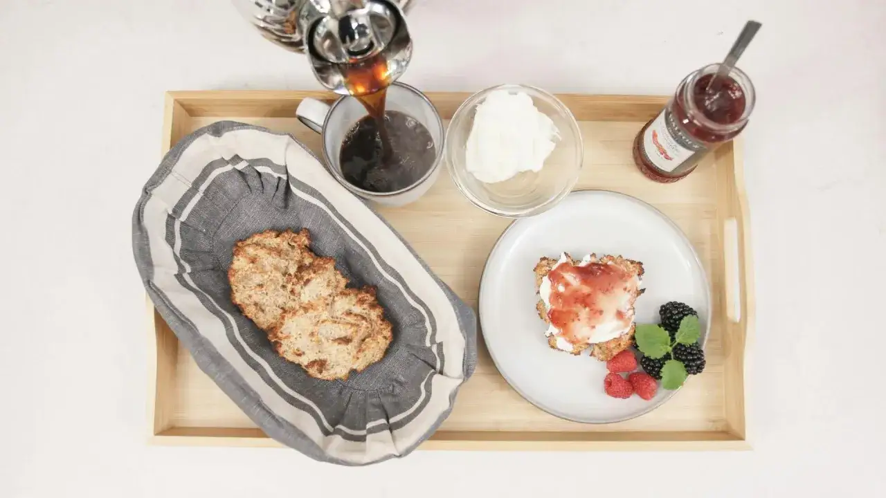 Frukostbricka med kaffe, scones med kvarg och sylt, samt färska bär.