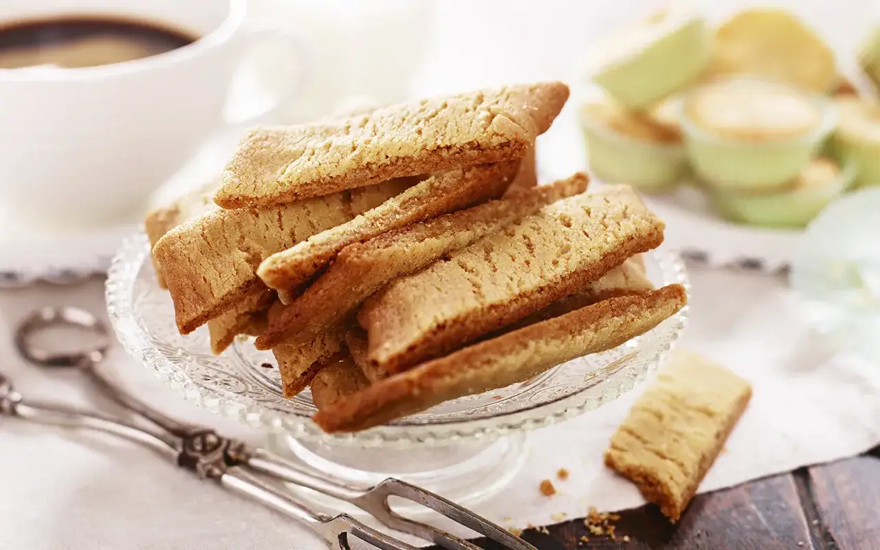 En hög med gyllene kolakakor på ett glasfat, redo att avnjutas med en kopp kaffe. Ett perfekt recept för hembakade godsaker.