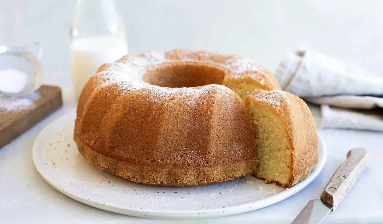En gyllene, gammaldags sockerkaka med ett snitt, pudrad med florsocker. En klassiker som doftar hembakat.