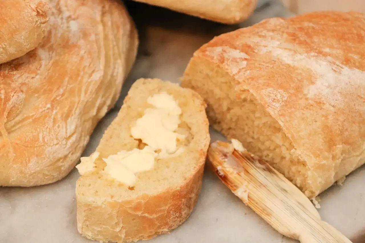 Nybakad ciabatta med smör på en skiva, perfekt för ett enkelt ciabatta recept.