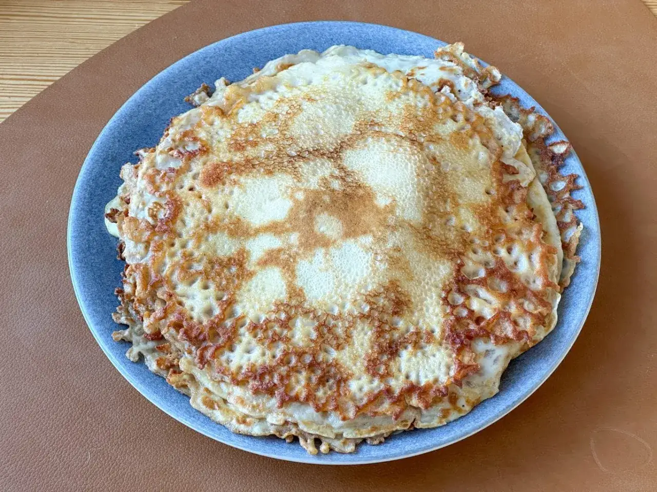 En hög med gyllene pannkakor på en blå tallrik. Undrar hur länge håller pannkakor i kylen?