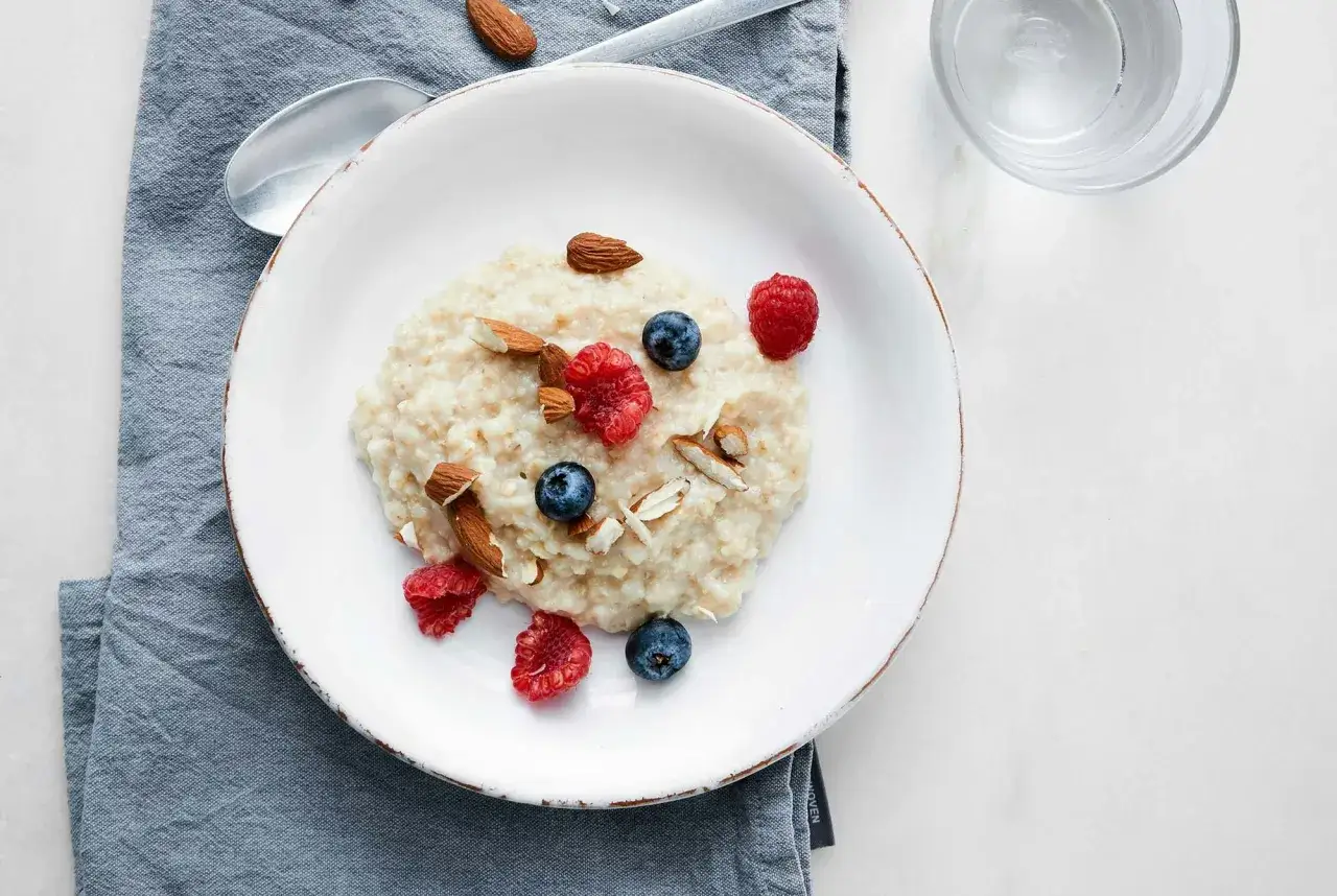 En skål med gröt toppad med hallon, blåbär och mandel. Perfekt för ett snabbt och gott overnight oats recept.