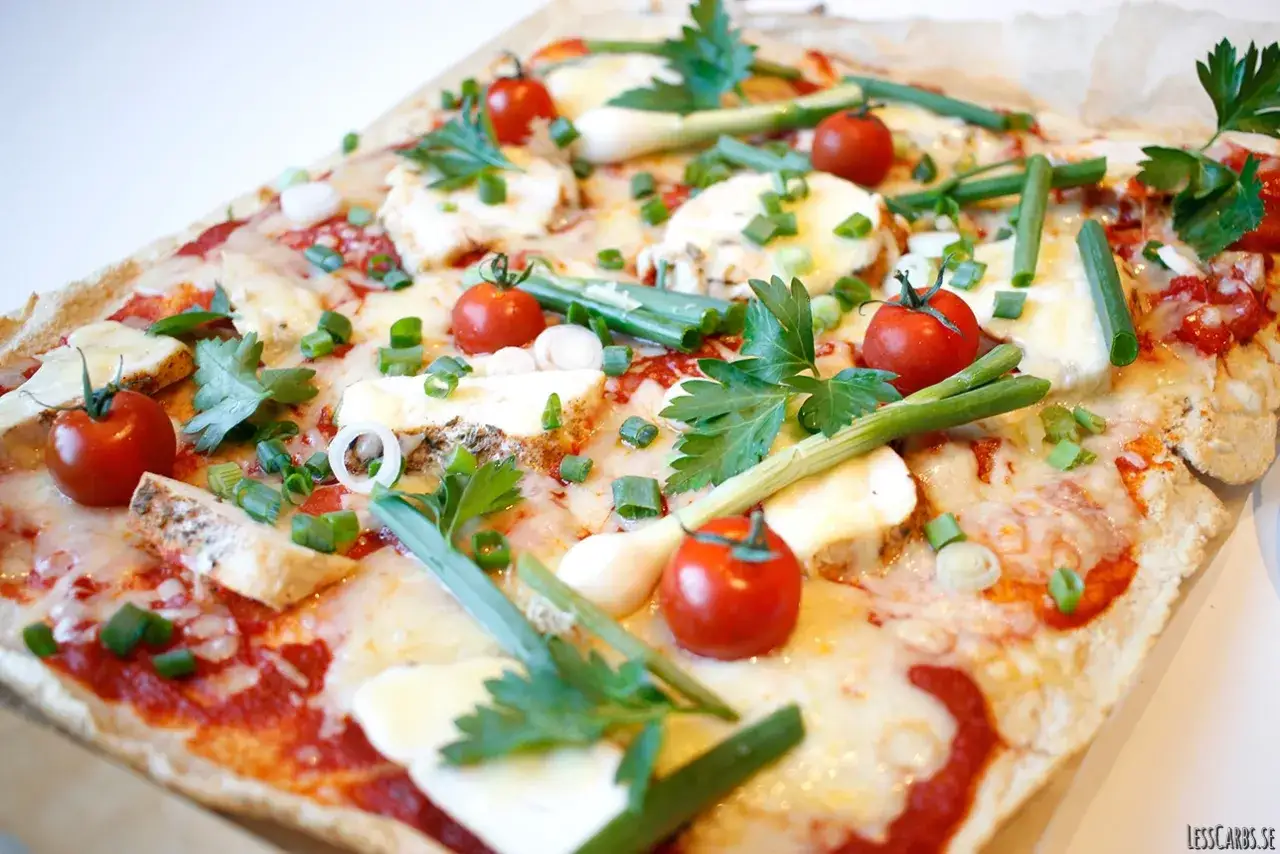 En l&auml;cker pizza med glutenfri pizzadeg recept, toppad med k&ouml;rsb&auml;rstomater, mozzarella och f&auml;rska &ouml;rter.