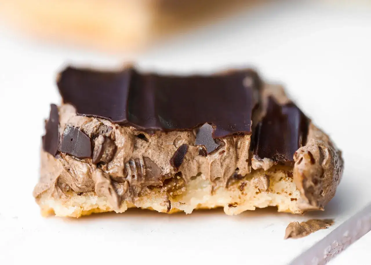 En bit av en chokladbiskvi i långpanna med krämig chokladmousse och mörk chokladglasyr.