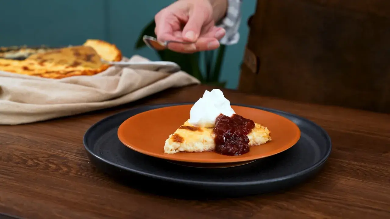 En bit ostkaka med vispad grädde och sylt. Ett perfekt recept för en fika.