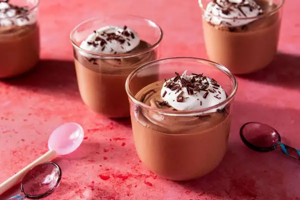 Chokladmousse recept: Krämig chokladmousse i glas, toppad med vispad grädde och chokladspån. Perfekt för en lyxig dessert.