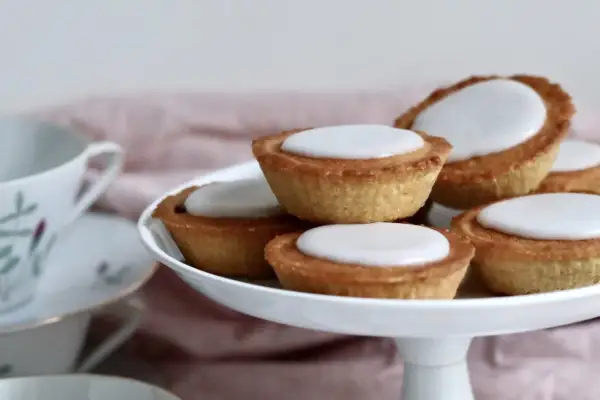 En hög med hembakade mazariner med vit glasyr, redo att avnjutas. Perfekt för ett fika-tillfälle, kanske med ett gott mazariner recept.