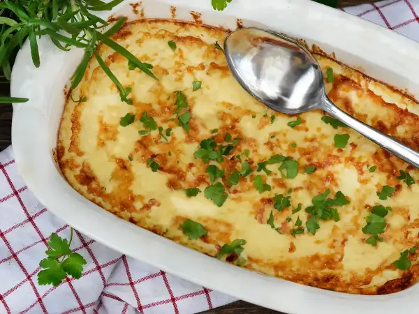 En gyllene omelett i ugn, toppad med färsk persilja och en sked redo att servera. Perfekt för en mysig frukost eller brunch.