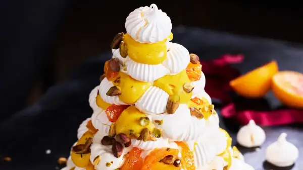 Julig pavlova i juletid, dekorerad med krämig vaniljkräm, aprikoser och pistagenötter.